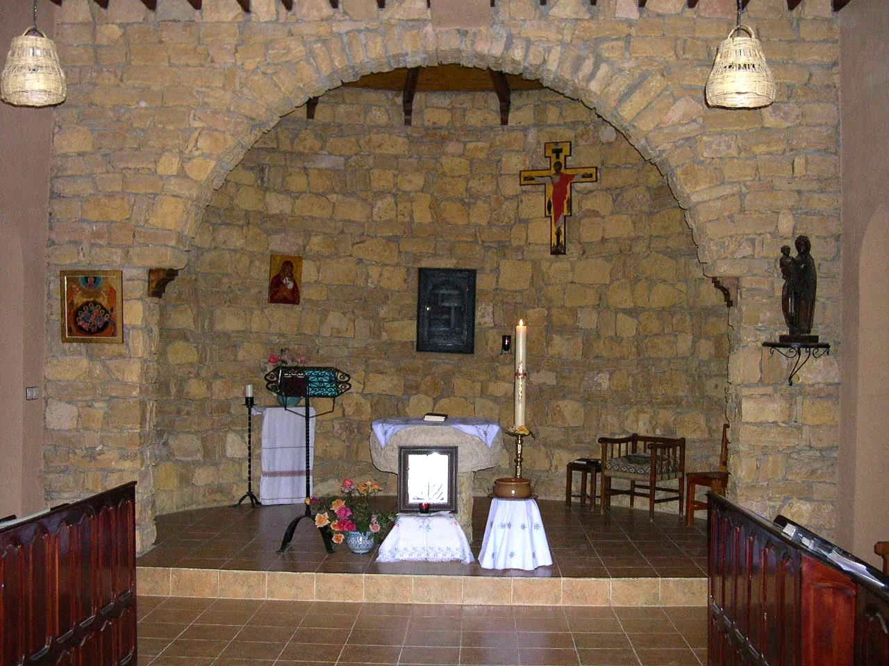 The stone-vaulted chapel of the Trappist priory of Notre-Dame de l'Atlas at Midelt, with a lit paschal candle, icons and a crucifix above the altar.