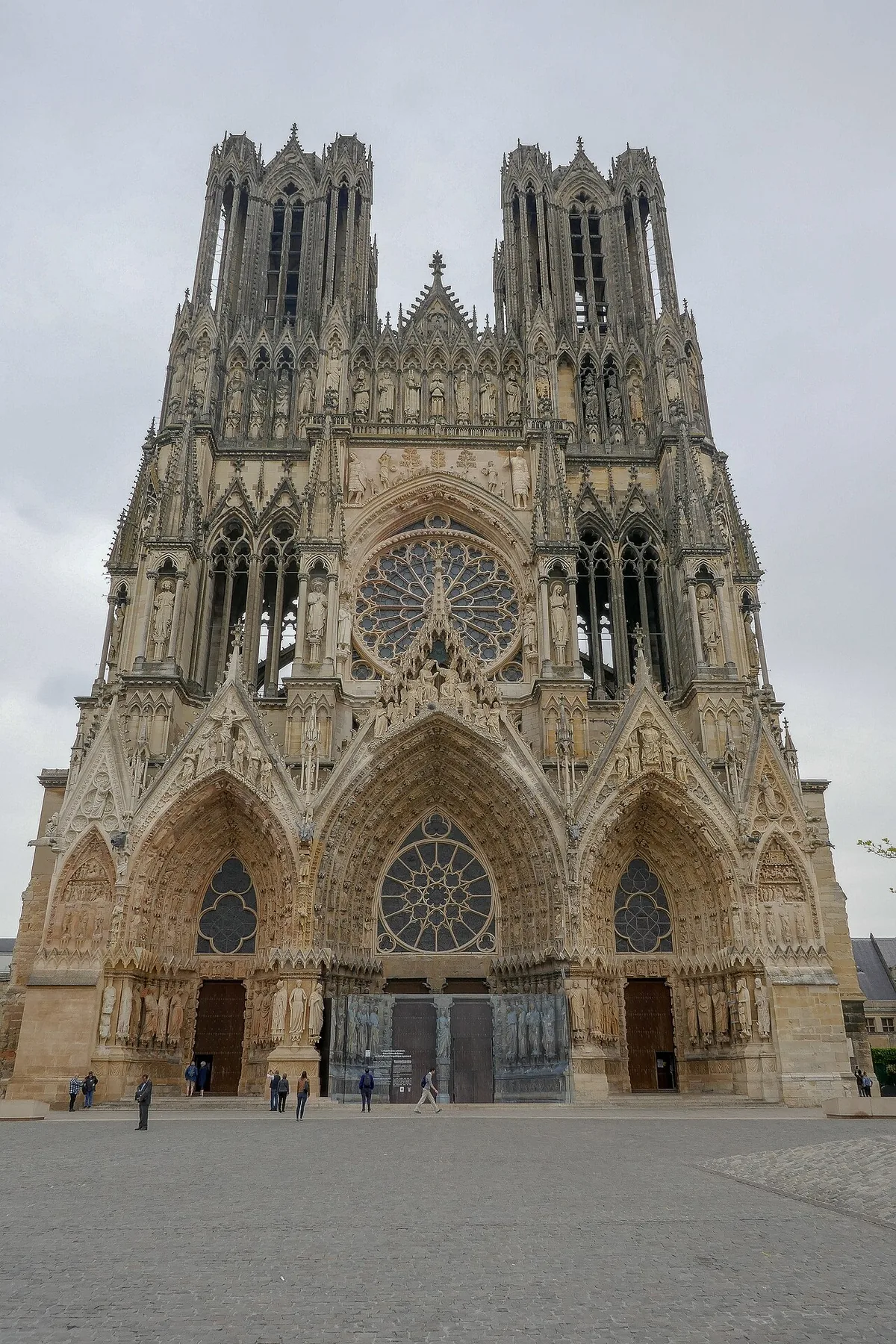 The west front of the cathedral of Notre-Dame de Reims, its three deep portals, gallery of kings and twin towers rising above the open parvis.