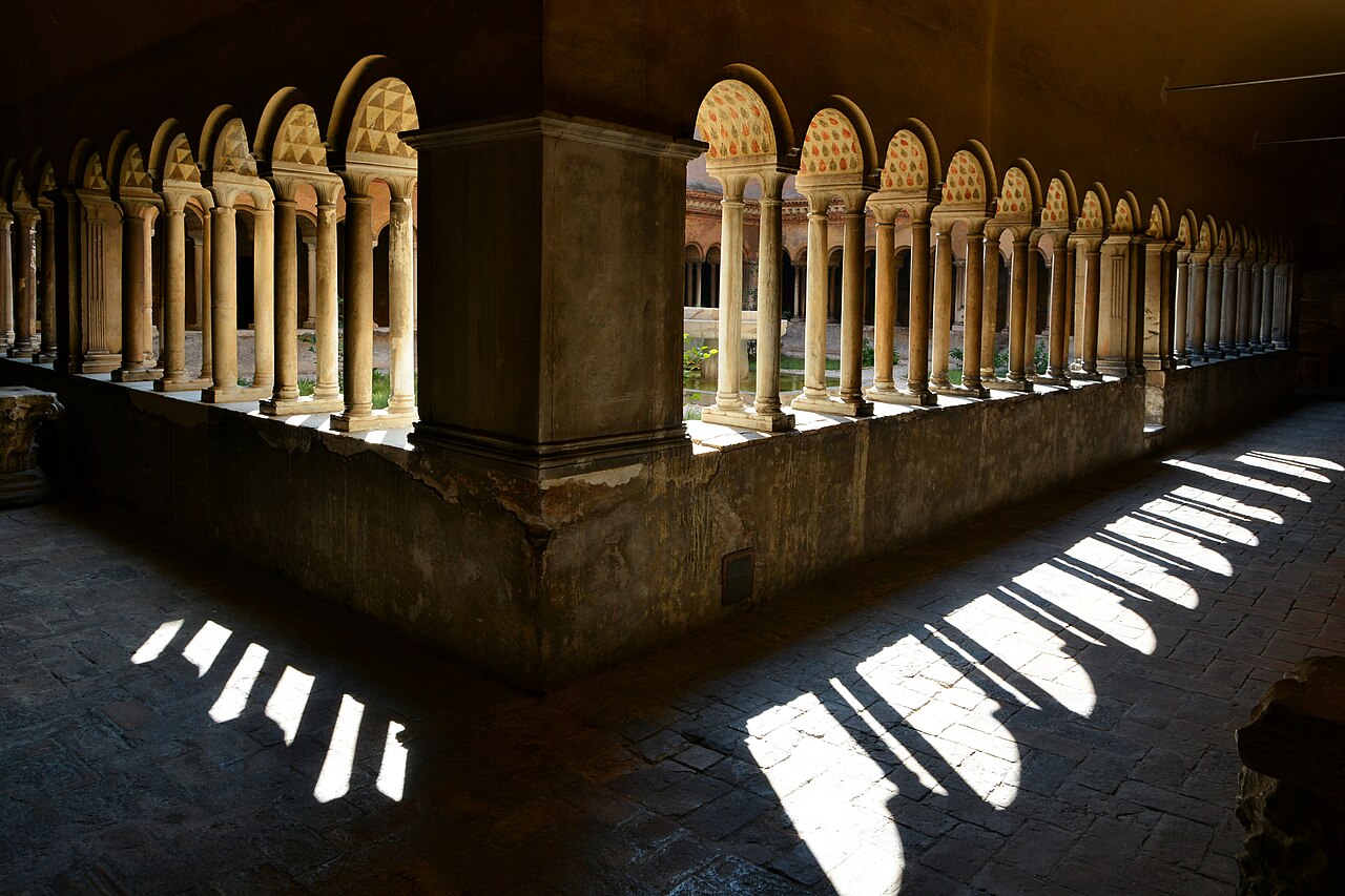 The colonnaded medieval cloister of Santi Quattro Coronati in Rome in low sunlight.