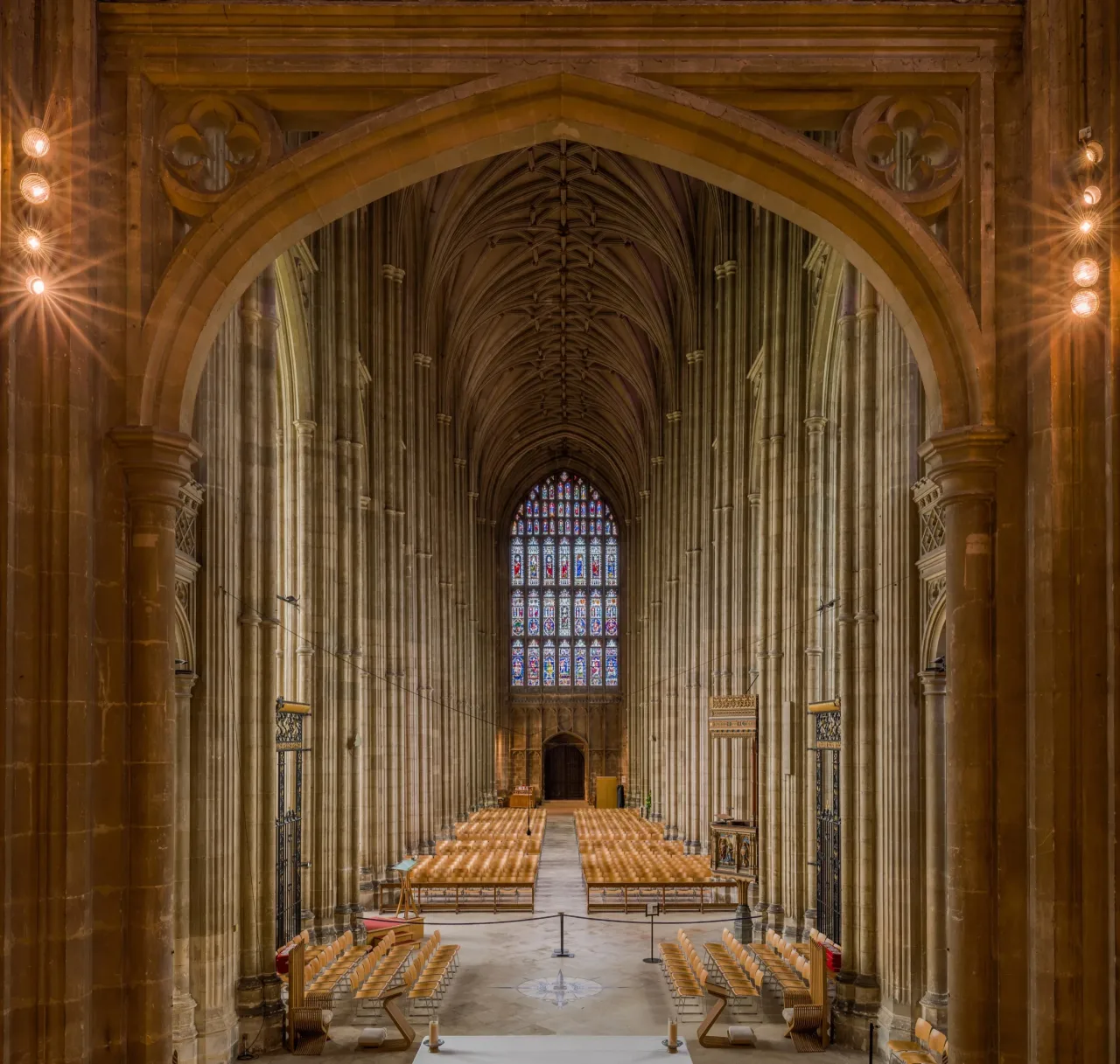 The Perpendicular nave of Canterbury Cathedral seen from the quire screen, its tall shafts rising to a lierne vault and the great west window.