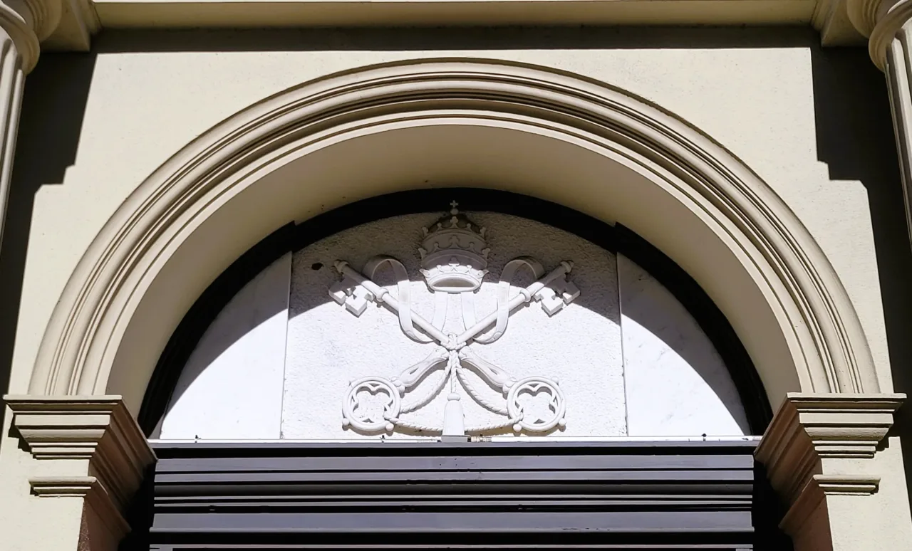 The crossed keys and papal tiara of a minor basilica carved in the arched tympanum above a doorway of the Cathedral Basilica of St. Augustine.
