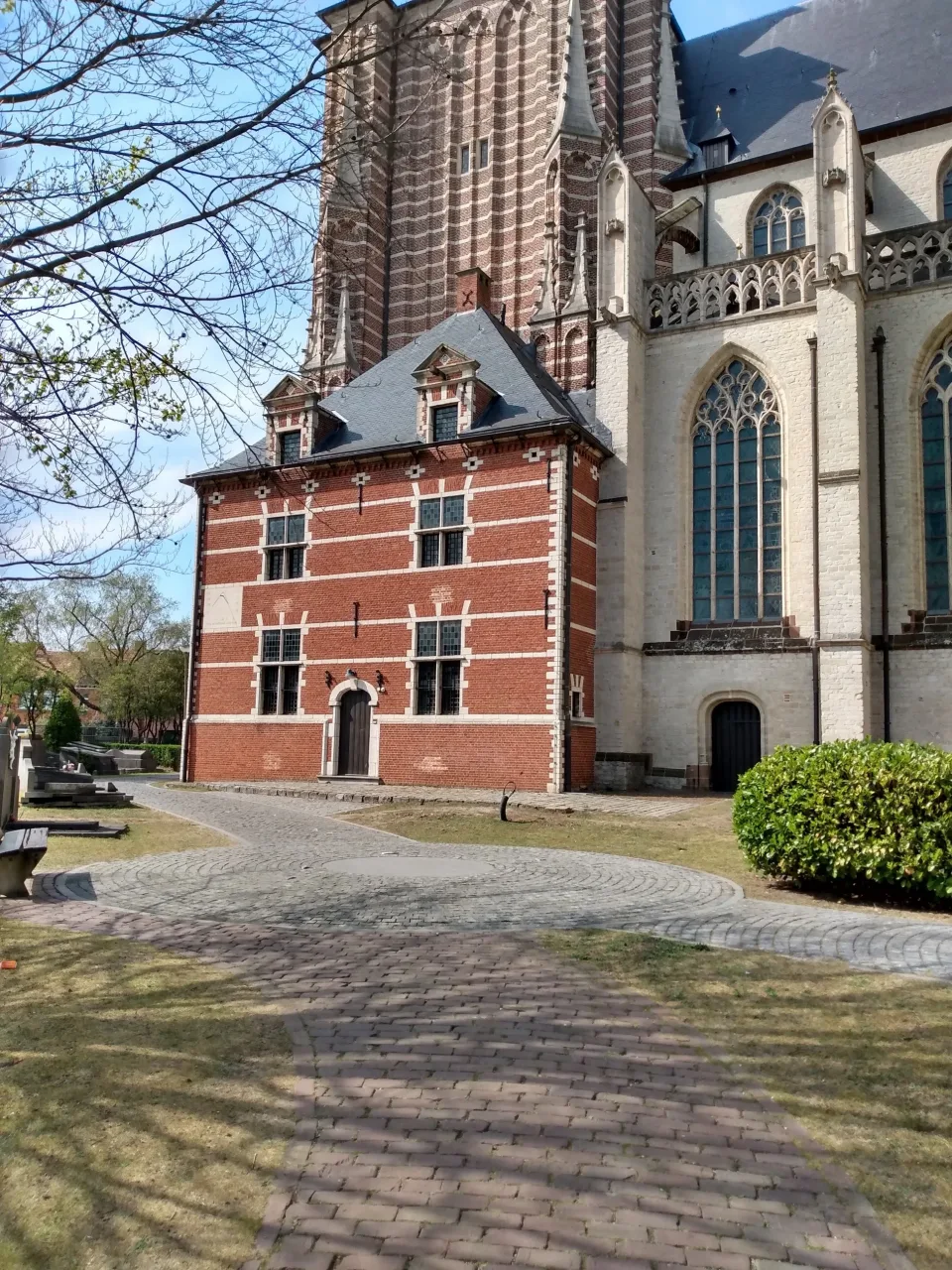 The Ziekenkamer at Geel, a red brick building with white stone banding built against the tower of the Sint-Dimpnakerk.