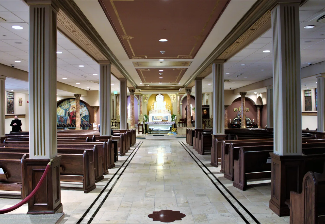 The lower church of the National Shrine of Saint John Neumann, with pews leading toward the shrine altar and saint’s tomb.