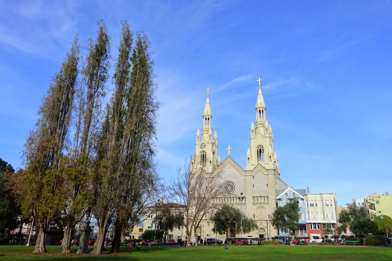 The twin-spired white facade of Saints Peter and Paul Church seen across the lawn of Washington Square in North Beach.