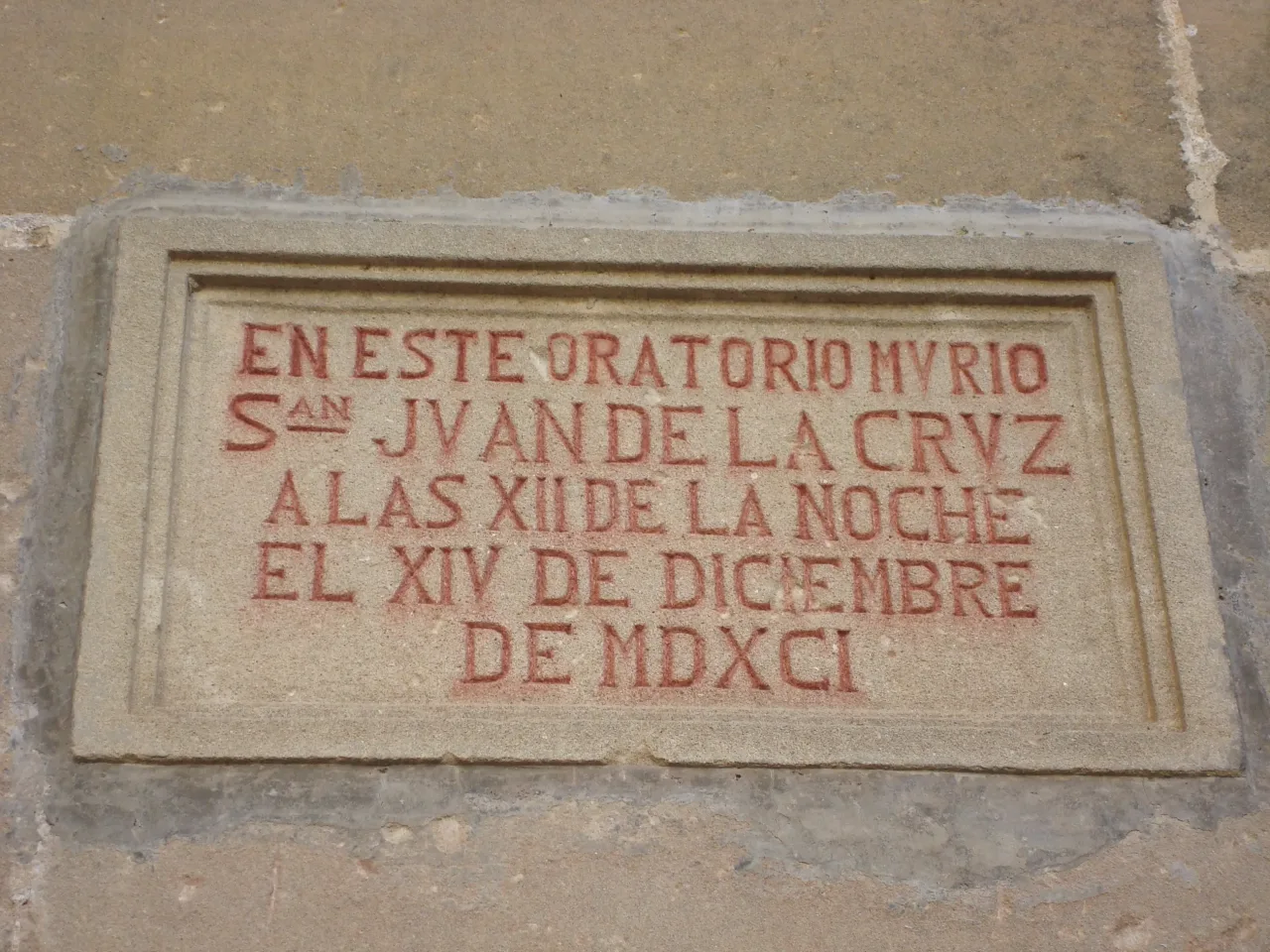 A carved stone tablet set into the wall at Ubeda, its red lettering reading that Saint John of the Cross died in this oratory at twelve at night on the fourteenth of December 1591.