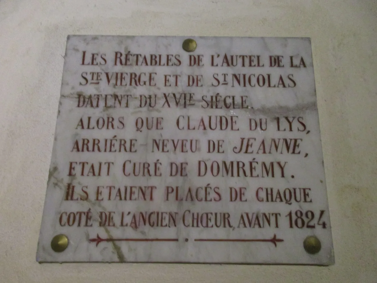 A marble plaque inside the church of Saint-Remy recording that the retables of the altars of the Blessed Virgin and Saint Nicholas date from the sixteenth century, when Claude du Lys, great-nephew of Joan, was cure of Domremy.