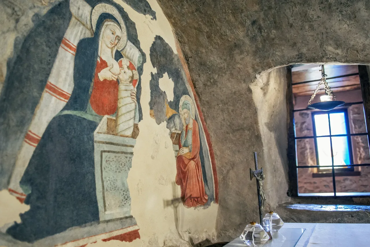 Detail of the Giottesque-school fresco in the Greccio chapel: the Virgin nursing the Child, beside the rock wall of the cave.