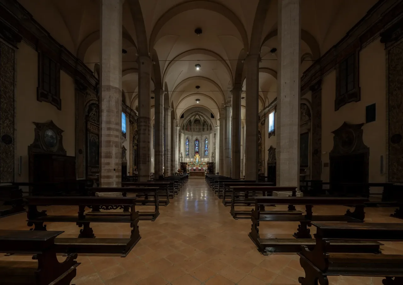 The nave of San Francesco in Gubbio, a long vaulted interior with columns and pews leading to a lit apse.