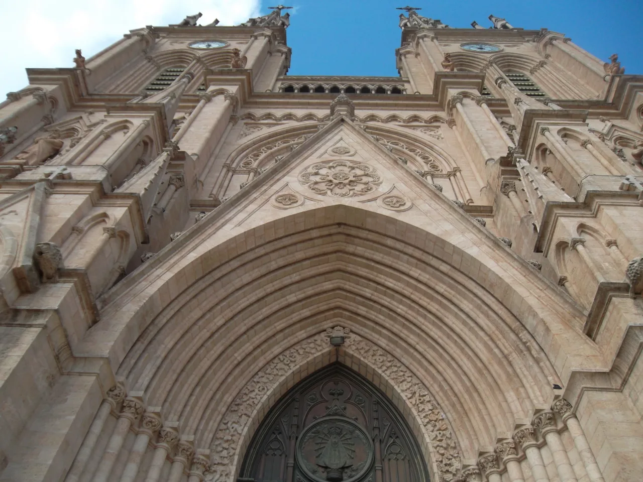 The carved entrance, rose window and twin towers of the Basilica of Our Lady of Luján, seen from below.