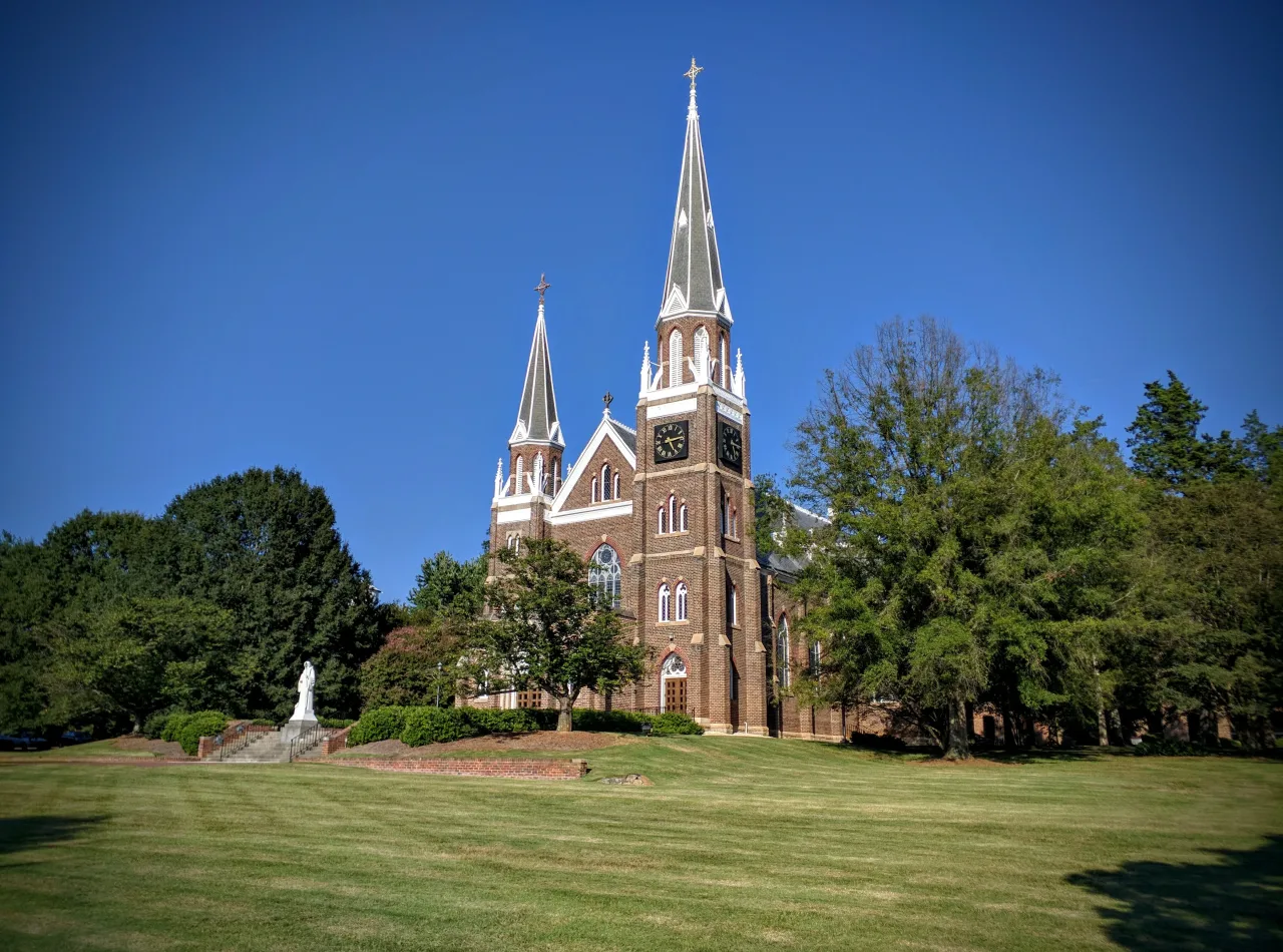 The brick Basilica of Mary Help of Christians and twin towers at Belmont Abbey, seen across the lawn.