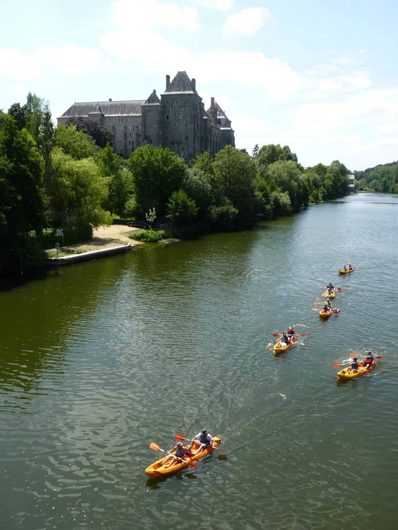 Saint-Pierre de Solesmes above the tree-lined Sarthe, with kayakers on the river below.