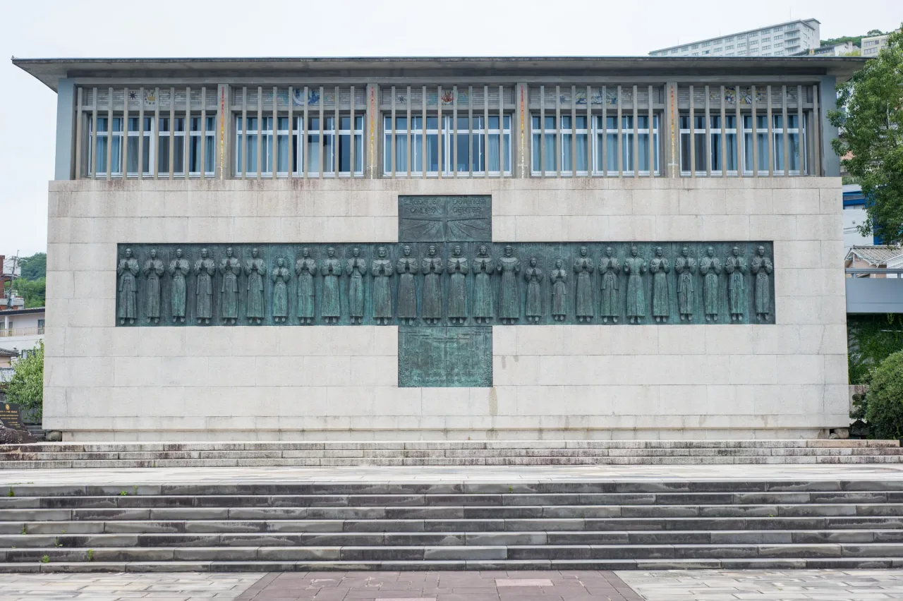 Yasutake Funakoshi's bronze relief of the Twenty-Six Martyrs, set in a cross on the monument wall at Nishizaka.