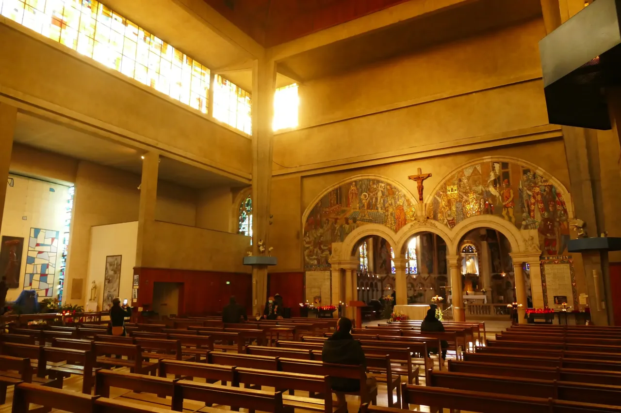 The interior of Notre-Dame-des-Miracles in Orleans, its plain twentieth-century nave with clerestory windows above a painted sanctuary arch and crucifix.