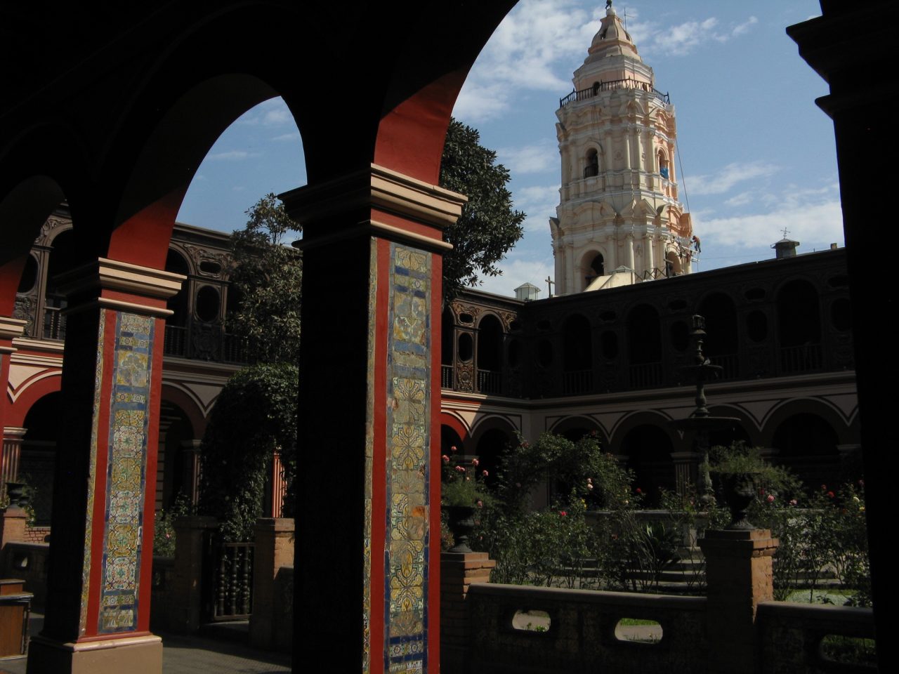 The tiled cloister of Santo Domingo in Lima, with its rose garden and the bell tower rising behind.