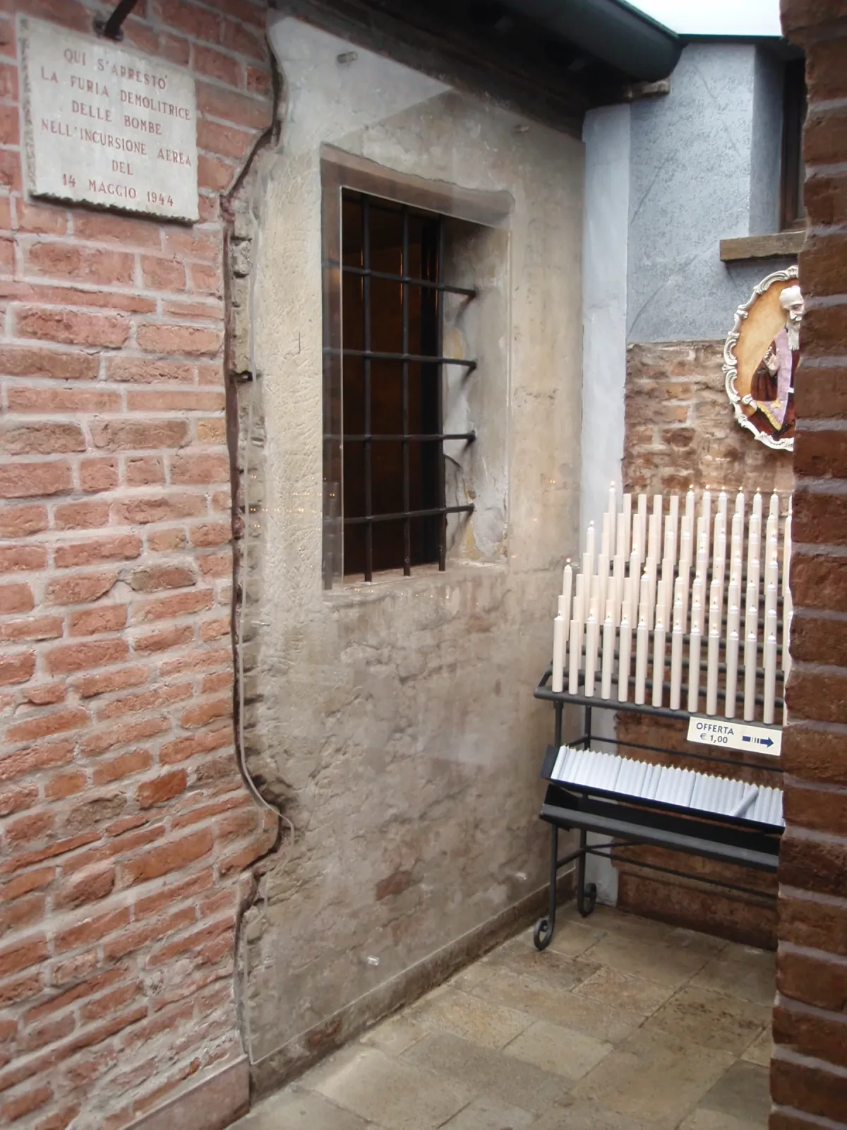 The small preserved confessional cell of Saint Leopold Mandić, with kneeler, candles, and devotional images.
