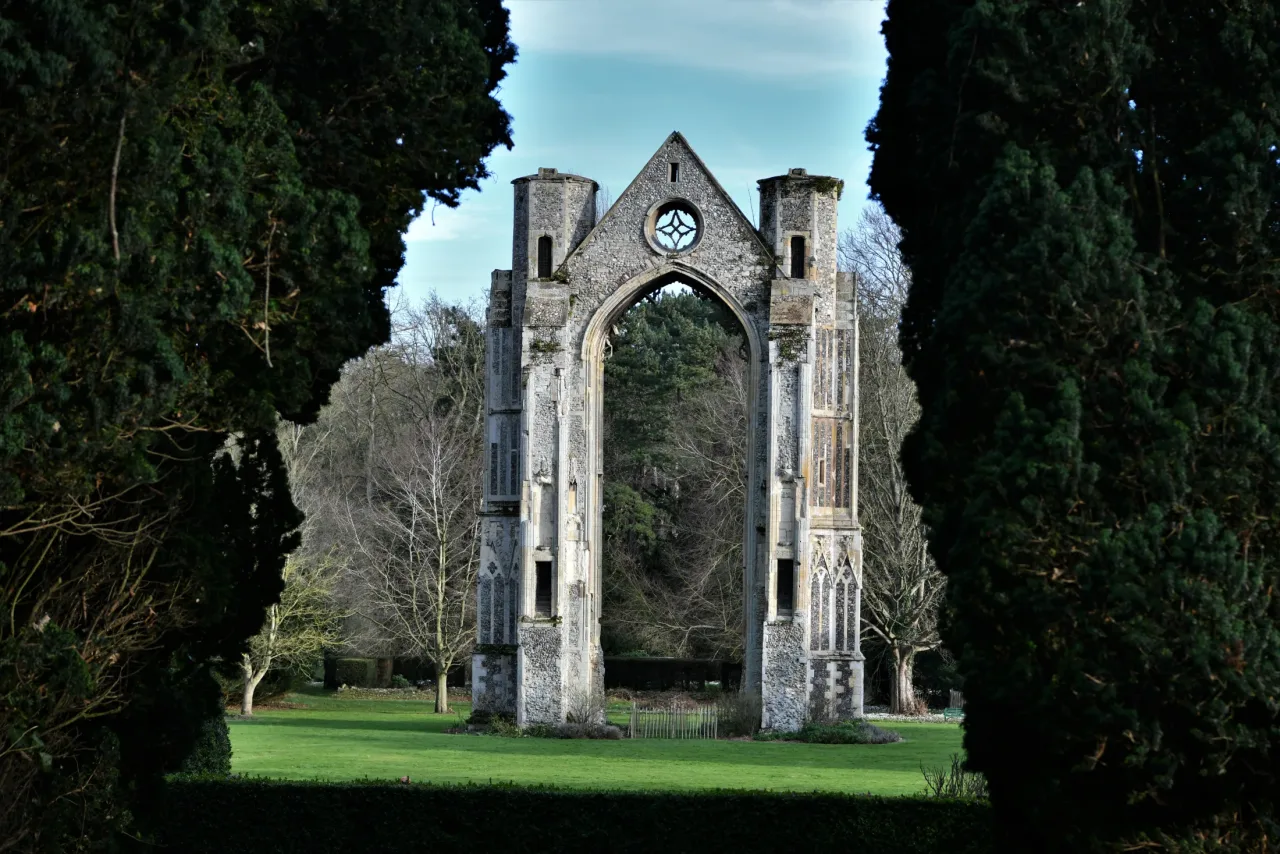 The surviving east window of the medieval Augustinian priory church at Walsingham, framed by trees.